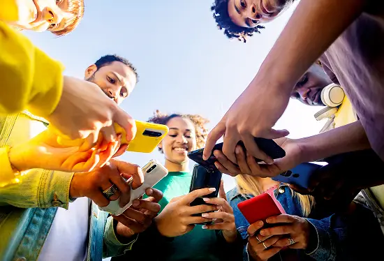 Young group of people using mobile phone outdoors.
