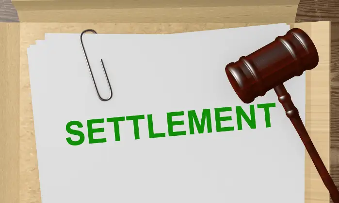 settlement written in green on paper with gavel