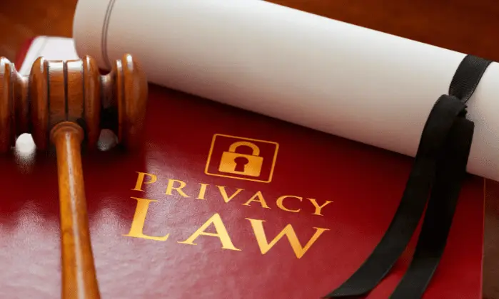 A gavel, a rolled legal document tied with a ribbon, and a book with the words "PRIVACY LAW" and a lock symbol