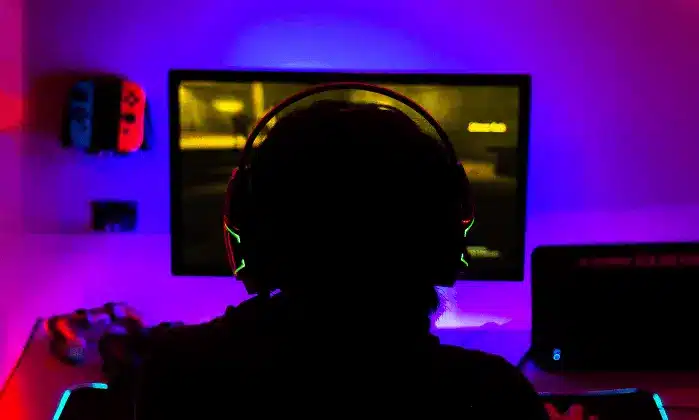 person sitting infront of computer with head phones on in the dark