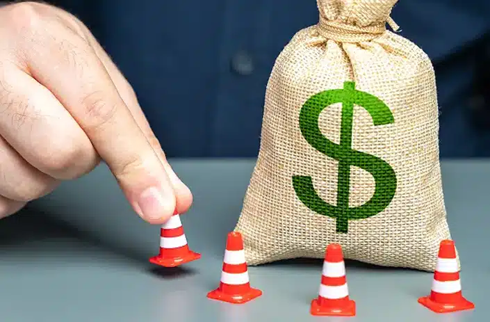 A man surrounds a dollar money bag with cones