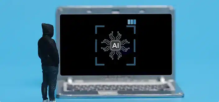 A person in a hooded jacket standing in front of a laptop displaying an AI (artificial intelligence) icon, represented by a circuit-like graphic