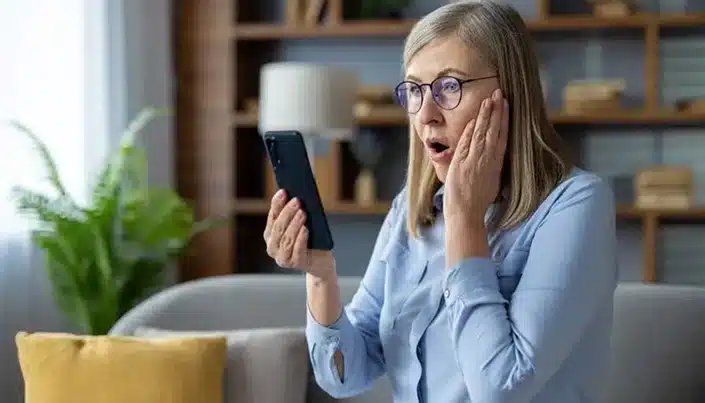 Shocked senior woman reacting to news on smartphone