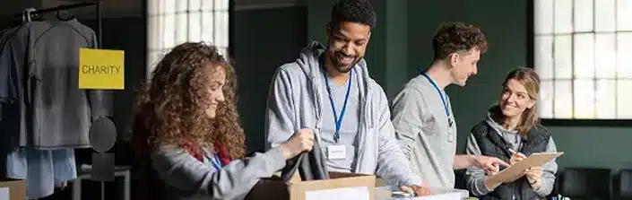 Volunteers working in community charity donation center sorting out clothes and canned food