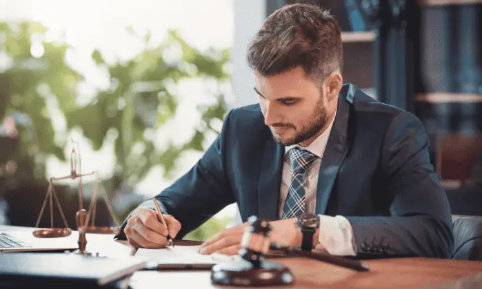 man in suit writing at desk