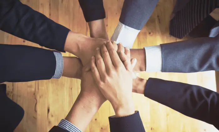 men in suits with their hands piled ontop of one another