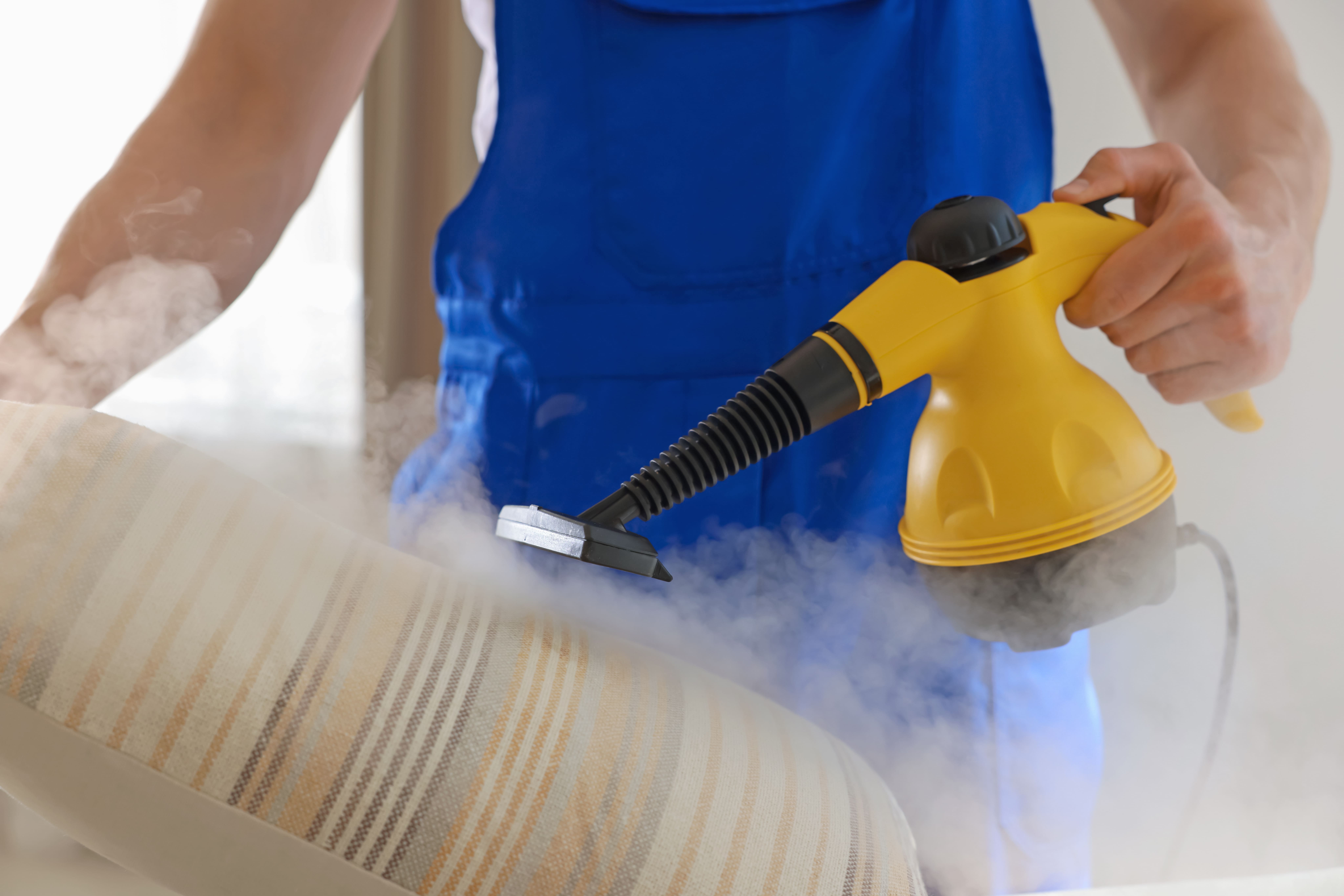 janitor cleaning pillow with steamcleaner at home