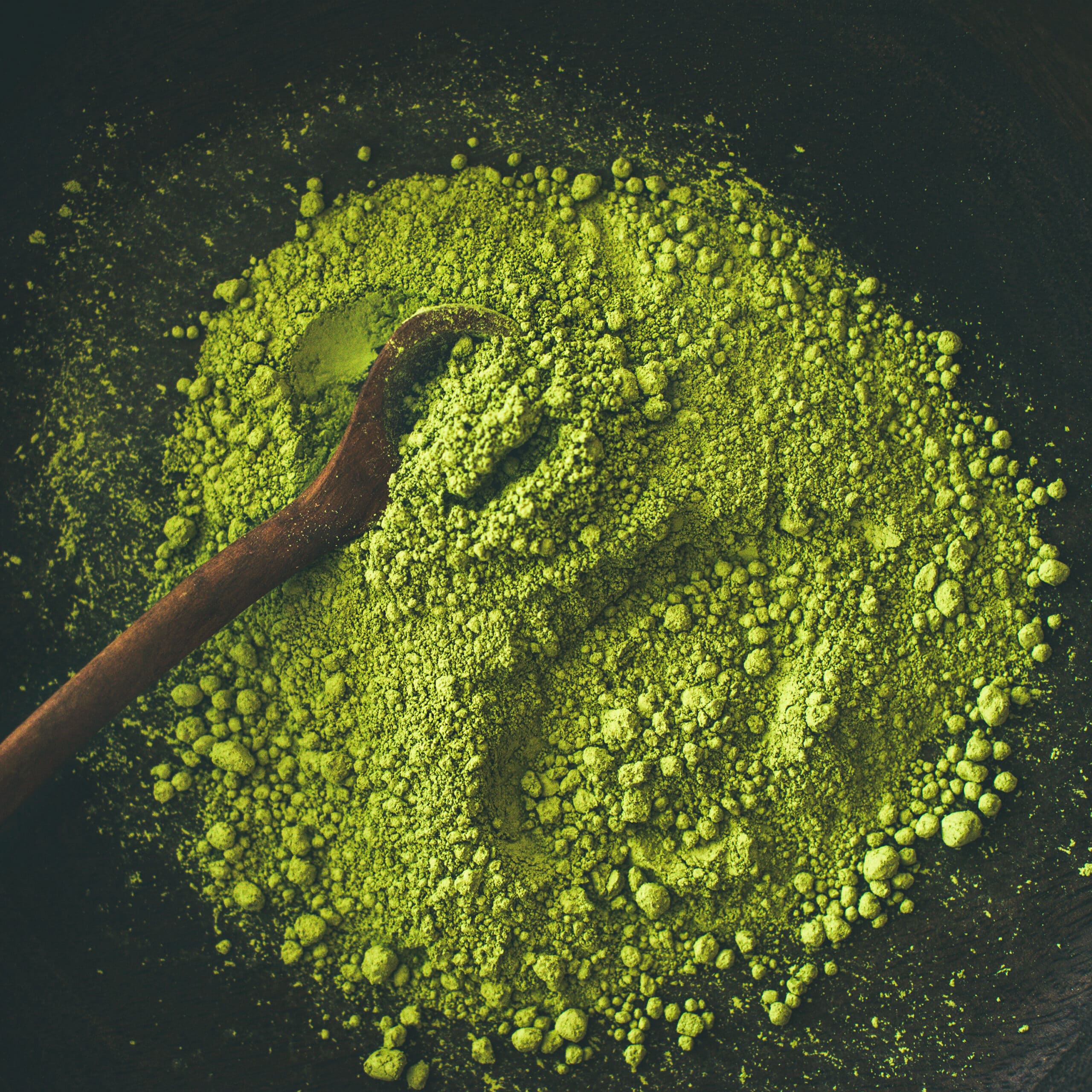 Japanese Matcha green tea powder in dark wooden bowl with spoon, top view, square crop. Clean eating, healthy, diet food concept