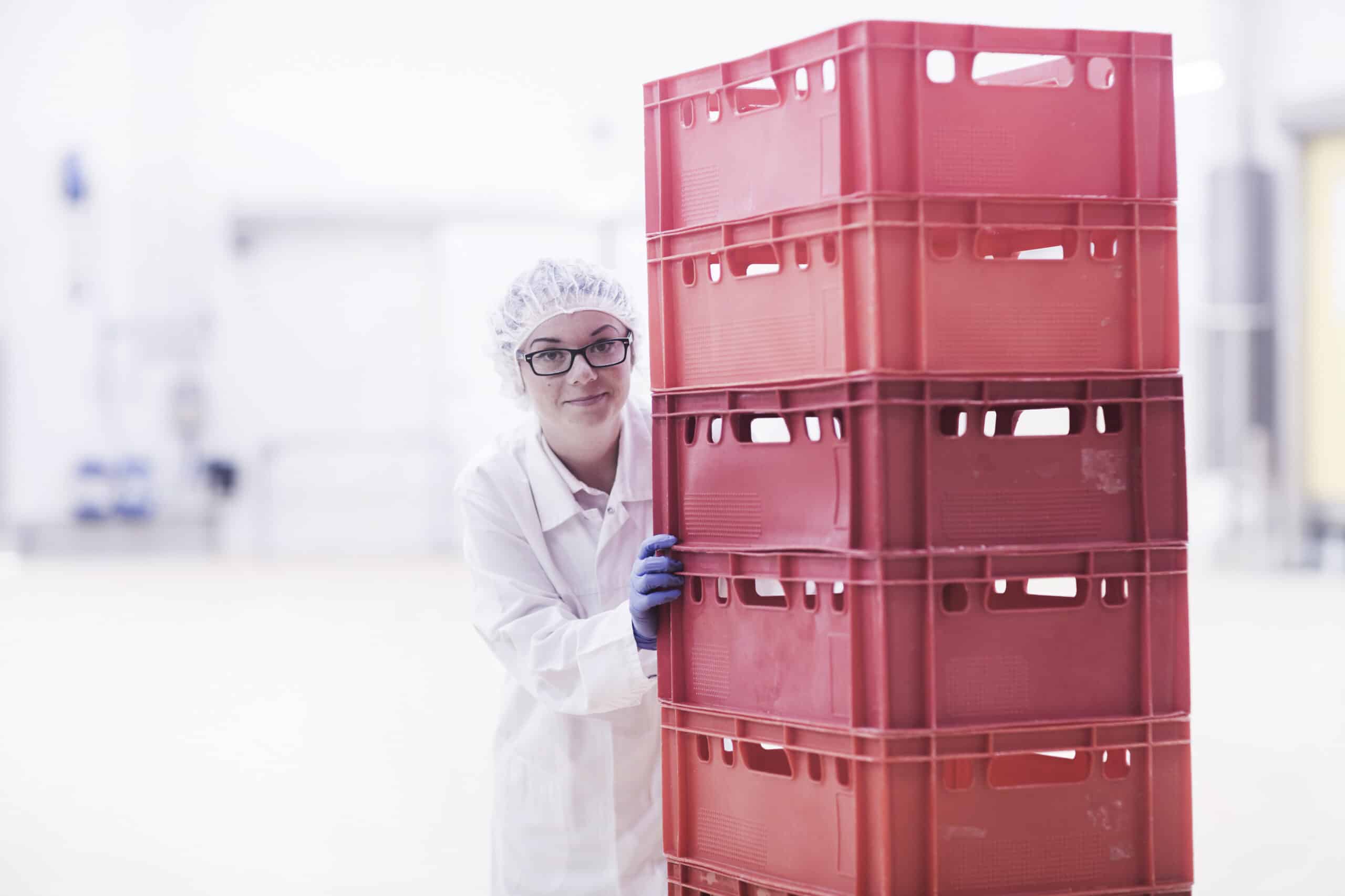 Factory worker pushing stacked crates