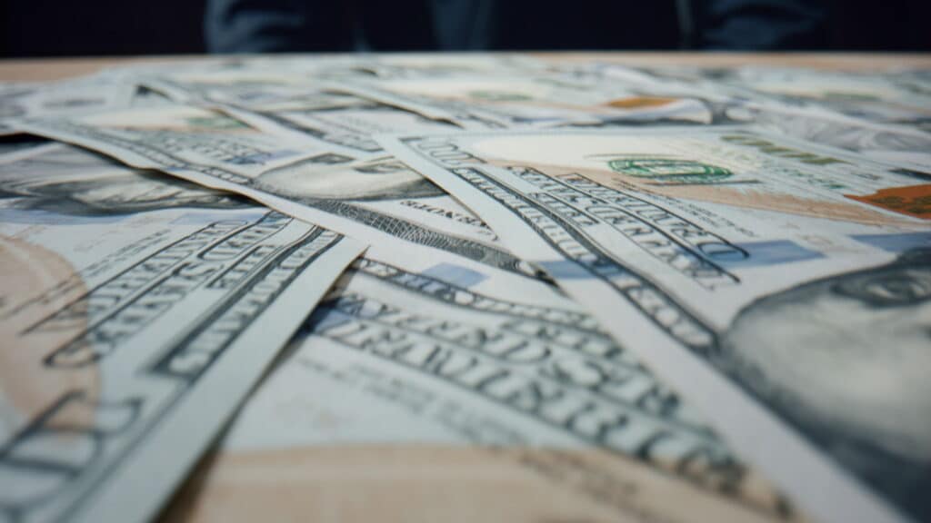Hundred dollar bills from a class action lawsuit settlement falling on large heap close up