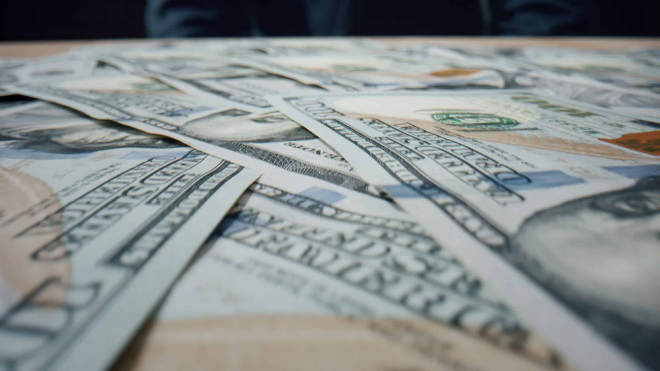 Hundred dollar bills from a class action lawsuit settlement falling on large heap close up