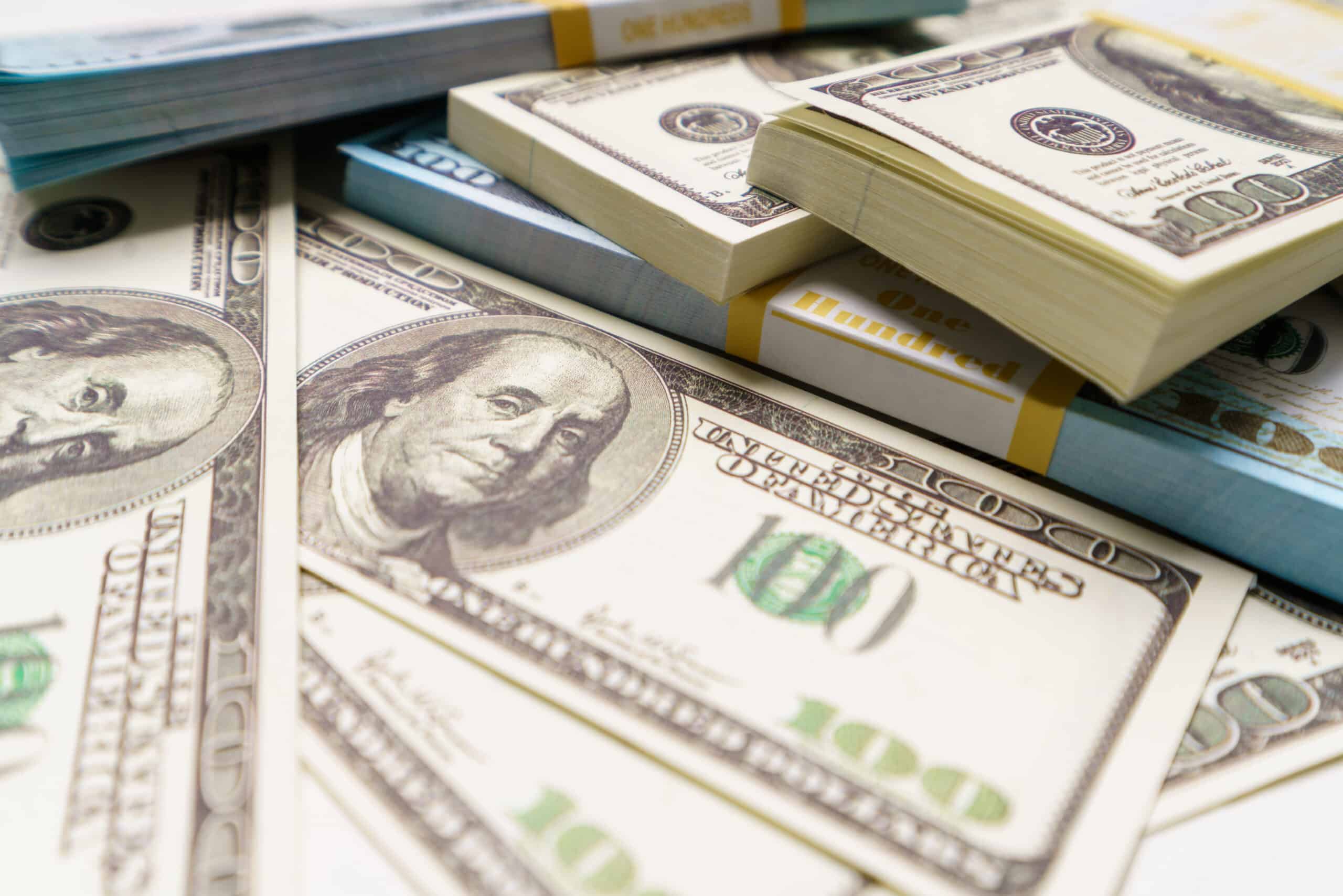 close-up photo of unclaimed class action lawsuit settlement money, hundreds of US dollar bills on a table