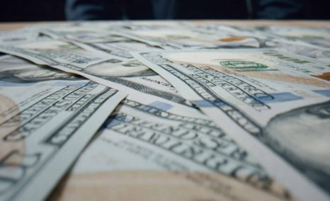 Hundred dollar bills from a class action lawsuit settlement falling on large heap close up