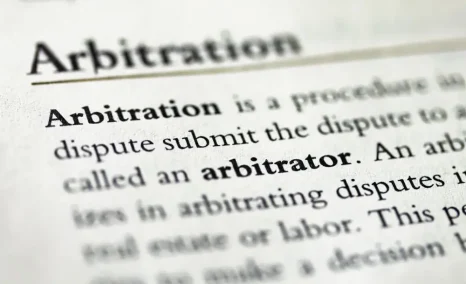 Close-up of a document defining arbitration, with the word “arbitrator” emphasized in bold text.