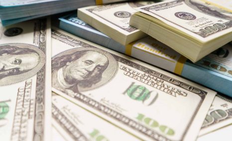 close-up photo of unclaimed class action lawsuit settlement money, hundreds of US dollar bills on a table