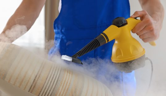Janitor cleaning pillow with steam cleaner at home, closeup