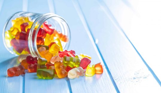 Jelly gummy bears candy. Colorful sweet confectionery on blue table.